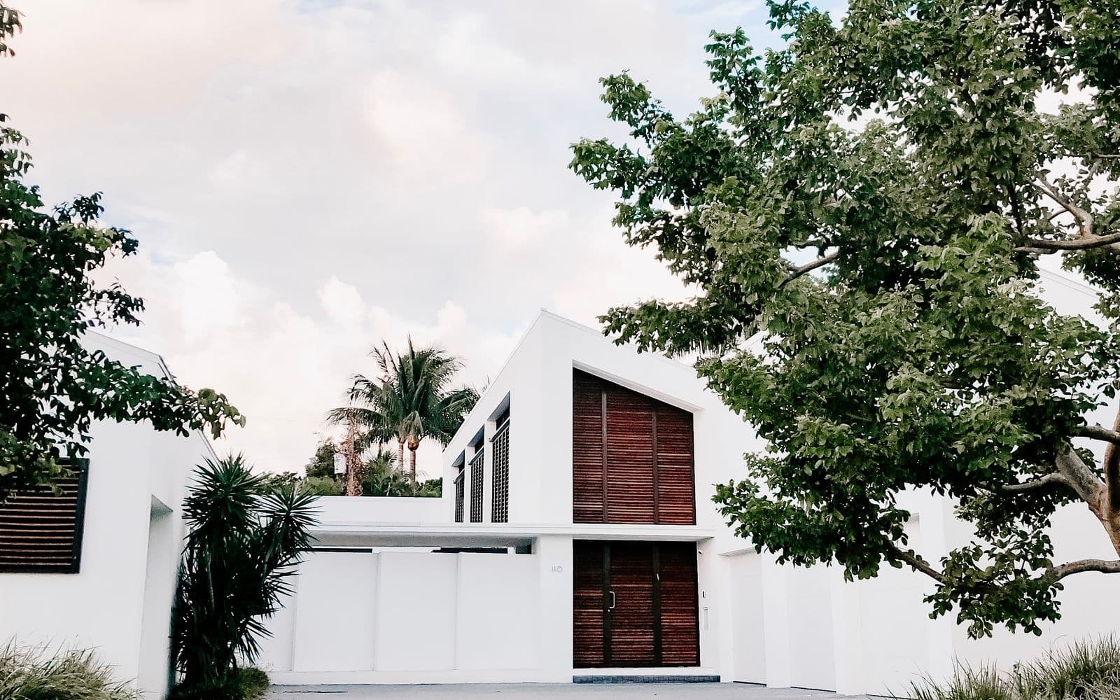 A clean, modern home exterior with fresh white siding and a paved driveway
